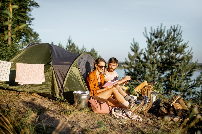 couple auprès d'une tente qui lit un livre couple auprès d'une tente qui lit un livre